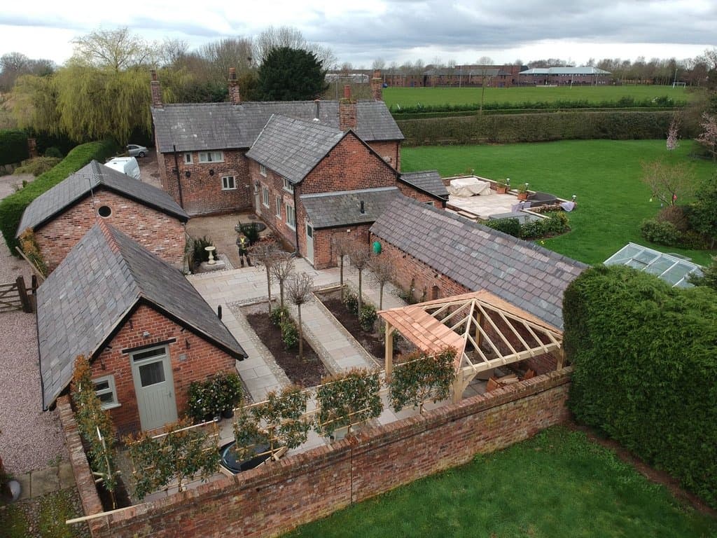 Finished walled courtyard garden at Yew Tree Farm, Appleton Thorn, with pleached trees, cobble-edged pathways and a bespoke gazebo